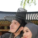 Dua orang mengenakan pakaian tradisional Korea di depan bangunan bergaya hanok