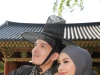 Dua orang mengenakan pakaian tradisional Korea di depan bangunan bergaya hanok