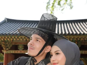 Dua orang mengenakan pakaian tradisional Korea di depan bangunan bergaya hanok