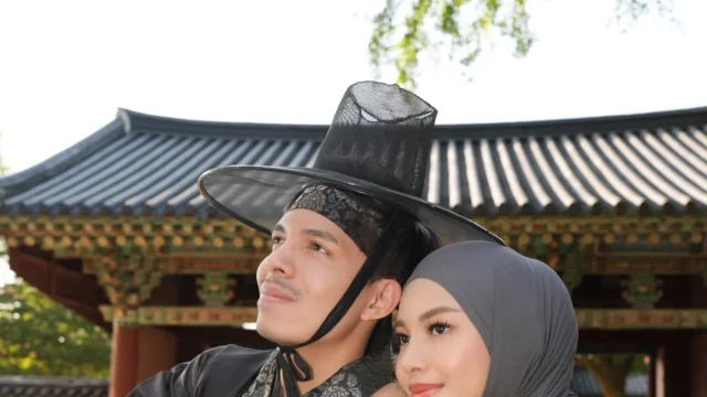 Dua orang mengenakan pakaian tradisional Korea di depan bangunan bergaya hanok