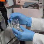 Peneliti menangani gelas kimia berisi sampel air di laboratorium