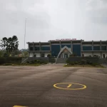 Gedung terminal Bandara Haji Muhammad Sidik dengan langit berkabut asap dan apron yang lengang.