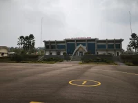 Gedung terminal Bandara Haji Muhammad Sidik dengan langit berkabut asap dan apron yang lengang.