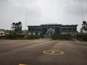 Gedung terminal Bandara Haji Muhammad Sidik dengan langit berkabut asap dan apron yang lengang.