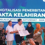 Sejumlah pejabat menyerahkan dokumen kependudukan kepada seorang ibu yang menggendong bayi pada peluncuran integrasi SATUSEHAT dan SIAK