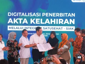 Sejumlah pejabat menyerahkan dokumen kependudukan kepada seorang ibu yang menggendong bayi pada peluncuran integrasi SATUSEHAT dan SIAK