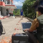 Petugas BMKG mengoperasikan peralatan survei seismik di halaman sebuah bangunan terdampak gempa.