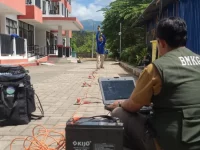 Petugas BMKG mengoperasikan peralatan survei seismik di halaman sebuah bangunan terdampak gempa.