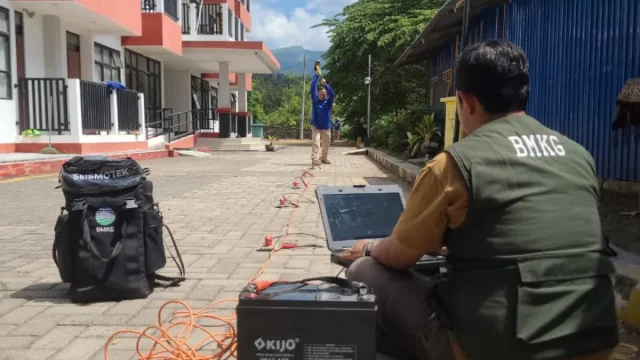 Petugas BMKG mengoperasikan peralatan survei seismik di halaman sebuah bangunan terdampak gempa.