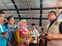 Pejabat BNPB berbincang dengan rombongan Kementerian Pemberdayaan Perempuan dan Perlindungan Anak di pos pendukung logistik bantuan.