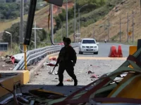 Seorang tentara berjalan di antara puing gerbang tol yang rusak akibat ledakan bom mobil di Cauca, Kolombia