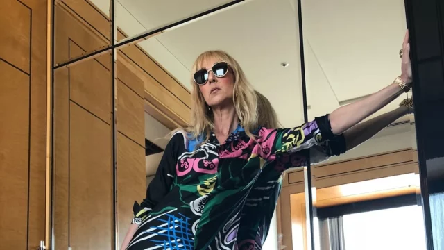 Celine Dion mengenakan busana bermotif warna-warni berpose di depan cermin