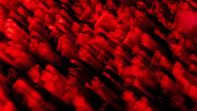 Kerumunan penonton konser tersorot cahaya panggung berwarna merah pekat
