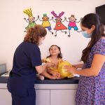 Ilustrasi dokter anak memeriksa bayi didampingi ibunya.