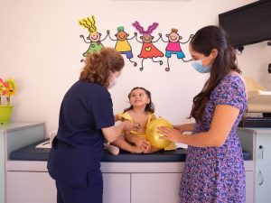 Ilustrasi dokter anak memeriksa bayi didampingi ibunya.