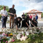 Warga meletakkan bunga dan lilin di tugu peringatan darurat depan sekolah