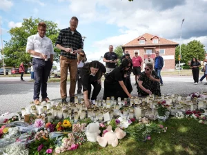 Warga meletakkan bunga dan lilin di tugu peringatan darurat depan sekolah
