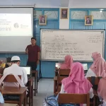 Guru memaparkan materi di depan kelas dengan proyektor
