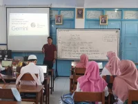 Guru memaparkan materi di depan kelas dengan proyektor