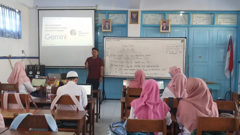 Guru memaparkan materi di depan kelas dengan proyektor