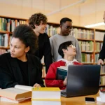 Sekelompok mahasiswa berdiskusi bersama dosen di perpustakaan kampus