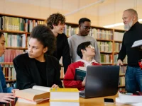 Sekelompok mahasiswa berdiskusi bersama dosen di perpustakaan kampus