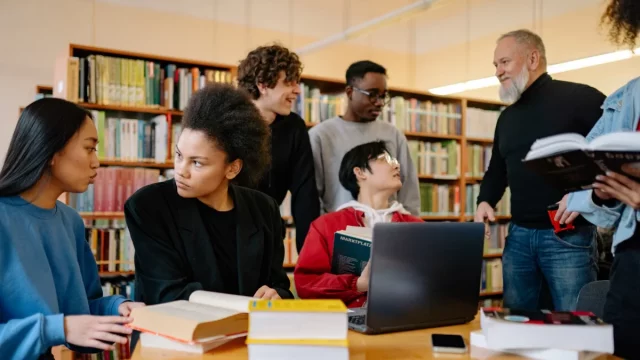 Sekelompok mahasiswa berdiskusi bersama dosen di perpustakaan kampus