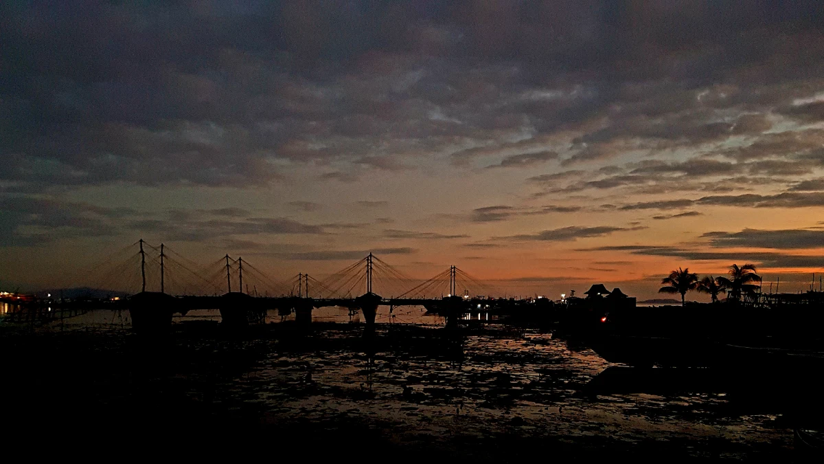 Dermaga tempat pelelangan ikan berbentuk siluet pada waktu senja.