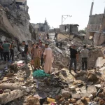 Warga Palestina memeriksa bangunan yang hancur di Jalur Gaza tengah
