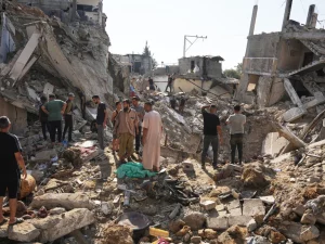 Warga Palestina memeriksa bangunan yang hancur di Jalur Gaza tengah