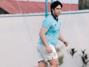 El Rumi berkaus biru muda menggiring bola di lapangan berumput sintetis