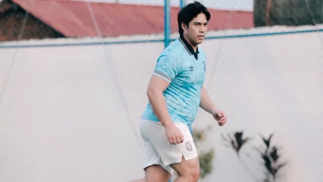 El Rumi berkaus biru muda menggiring bola di lapangan berumput sintetis