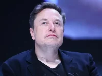 Elon Musk mengenakan jas hitam menatap ke atas dalam sebuah acara