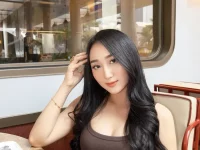 Sandrina Mazayya duduk di kursi berlengan sebuah kafe dengan jendela kaca besar di belakangnya.