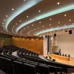 Ruang auditorium modern dengan deretan kursi menghadap panggung
