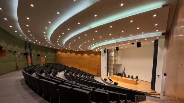 Ruang auditorium modern dengan deretan kursi menghadap panggung