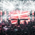 Penampil di atas panggung konser dengan tata cahaya terang