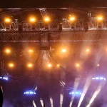 Kerumunan penonton konser di bawah lampu panggung terang