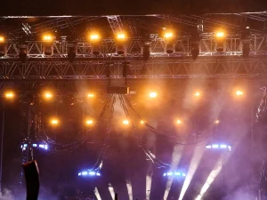 Kerumunan penonton konser di bawah lampu panggung terang