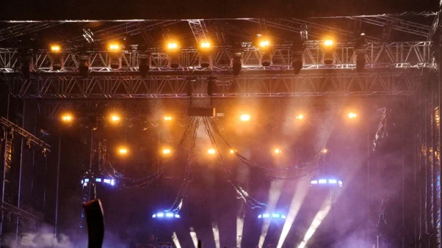 Kerumunan penonton konser di bawah lampu panggung terang