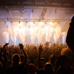 Penonton menikmati konser dengan efek cahaya dan asap