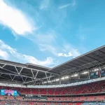 Penonton memenuhi tribune stadion sepak bola pada siang hari