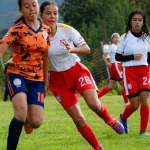Beberapa pemain sepak bola putri berduel memperebutkan bola di lapangan rumput