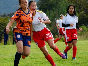 Beberapa pemain sepak bola putri berduel memperebutkan bola di lapangan rumput