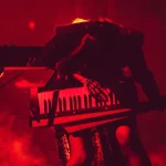 Isyana Sarasvati tampil dramatis di atas panggung dengan pencahayaan merah sambil memainkan keytar
