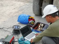 Peneliti bertopi keselamatan memantau data pada laptop saat persiapan demonstrasi guncangan gempa pada prototipe bangunan tahan gempa di Ponorogo.