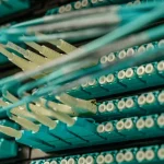Untaian kabel serat optik terhubung ke rak perangkat jaringan