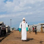 Petugas kesehatan berpakaian alat pelindung diri lengkap bersiap mendisinfeksi area pemakaman korban Ebola di kamp pengungsi Kigonze, Bunia, Republik Demokratik Kongo.