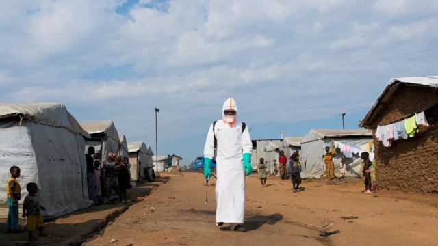 Petugas kesehatan berpakaian alat pelindung diri lengkap bersiap mendisinfeksi area pemakaman korban Ebola di kamp pengungsi Kigonze, Bunia, Republik Demokratik Kongo.