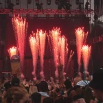 Semburan kembang api panggung di depan layar besar pada sebuah festival musik terbuka